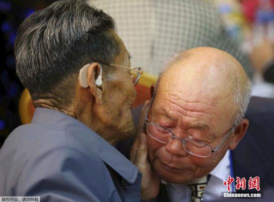 来自朝鲜的82岁老人Kim Duk Young与80岁的弟弟Kim Chang-young见面后贴耳交谈。